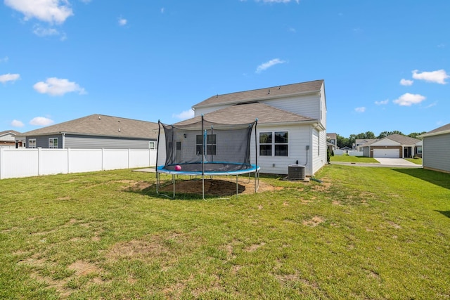 rear view of property with a trampoline and a yard