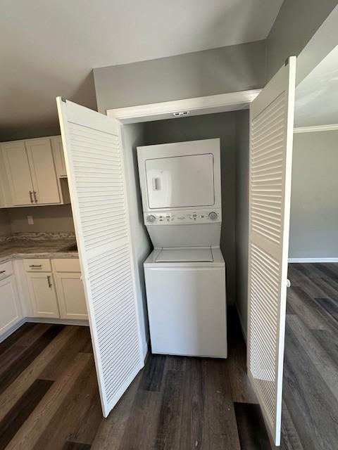 laundry area featuring stacked washer and clothes dryer and dark hardwood / wood-style flooring