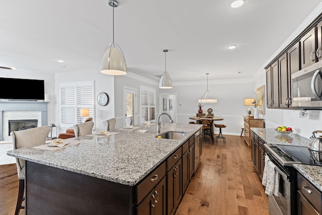 kitchen with hanging light fixtures, an island with sink, appliances with stainless steel finishes, and sink