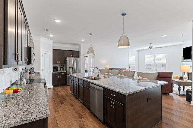 kitchen with hanging light fixtures, appliances with stainless steel finishes, a kitchen island with sink, and sink