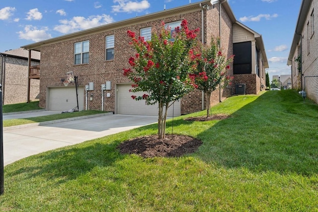 view of front of property with a garage, central AC, and a front lawn