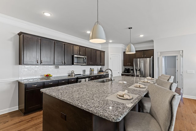 kitchen featuring dark brown cabinetry, stainless steel appliances, sink, and an island with sink