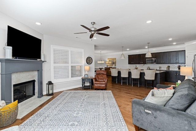 living room featuring light hardwood / wood-style flooring, ornamental molding, and ceiling fan