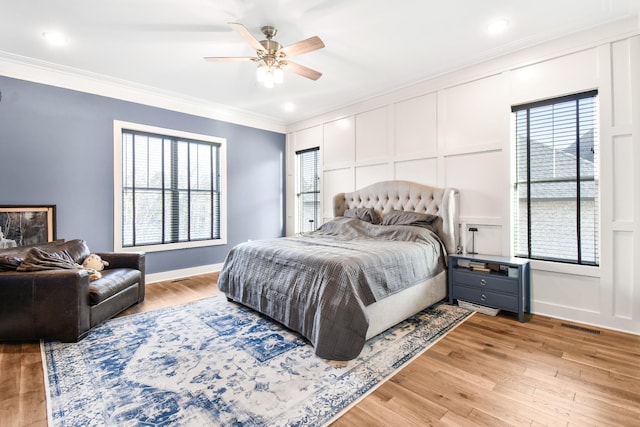 bedroom with crown molding, multiple windows, and light hardwood / wood-style flooring