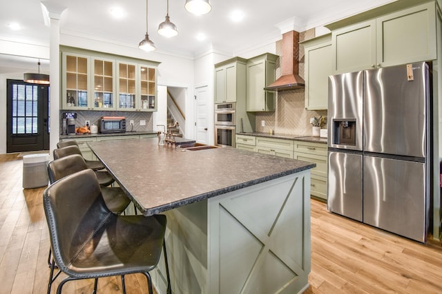 kitchen featuring a breakfast bar, decorative light fixtures, ornamental molding, appliances with stainless steel finishes, and green cabinets