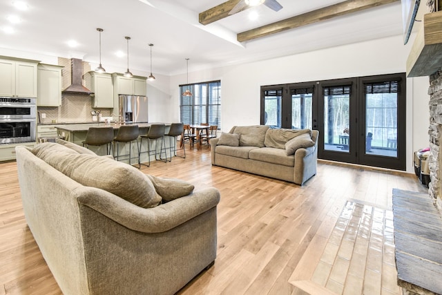 living room with beam ceiling, light hardwood / wood-style floors, french doors, and ceiling fan