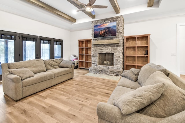 living room with ceiling fan, a stone fireplace, beam ceiling, and light hardwood / wood-style flooring