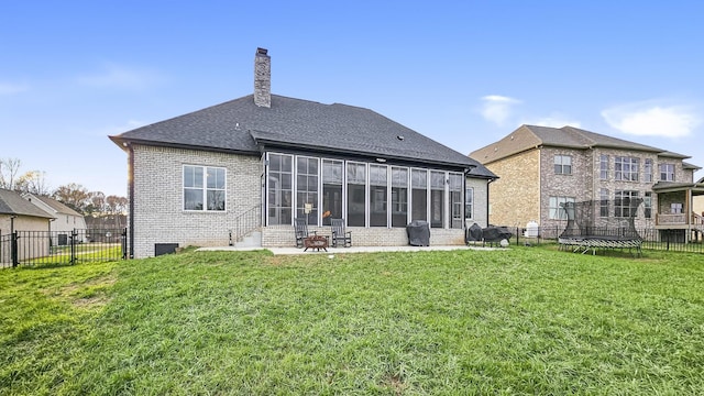 back of house with a trampoline, a lawn, a sunroom, and a patio