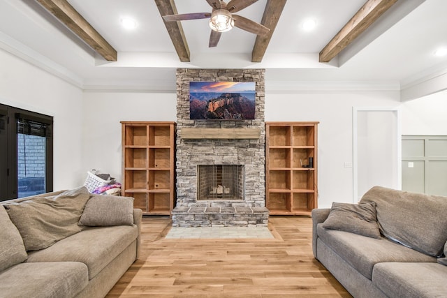 living room with beam ceiling, a stone fireplace, light hardwood / wood-style flooring, and ceiling fan