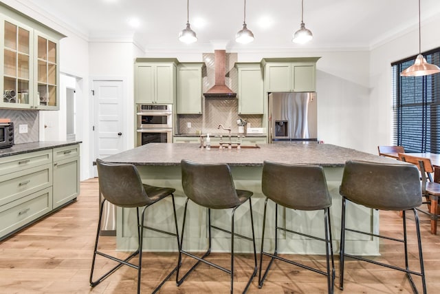 kitchen with premium range hood, a breakfast bar area, appliances with stainless steel finishes, green cabinets, and pendant lighting