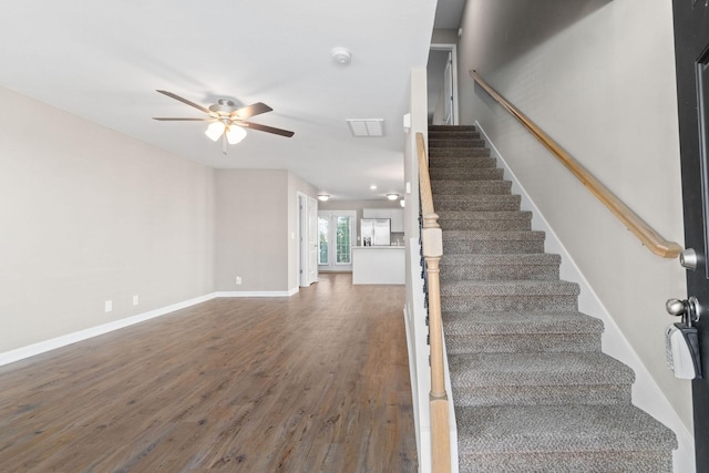 stairs featuring hardwood / wood-style flooring and ceiling fan