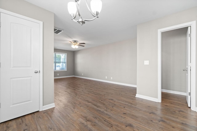 empty room with dark hardwood / wood-style flooring and ceiling fan with notable chandelier