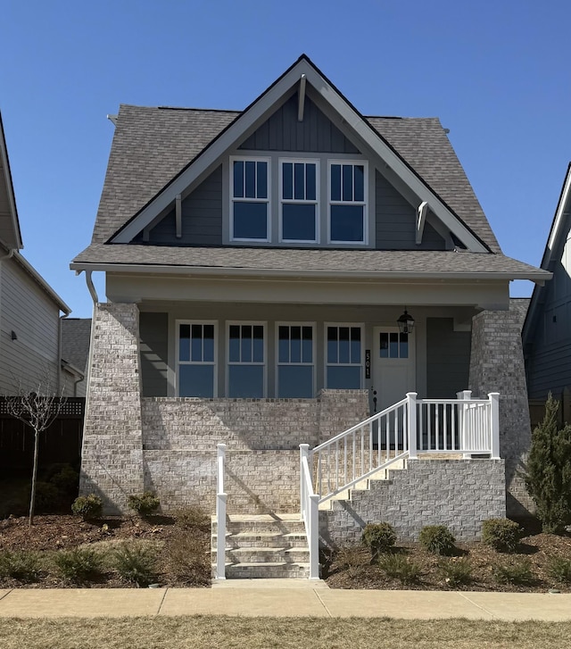 view of front facade featuring covered porch, a shingled roof, and board and batten siding