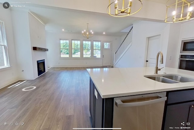 kitchen with appliances with stainless steel finishes, open floor plan, an inviting chandelier, a fireplace, and a sink