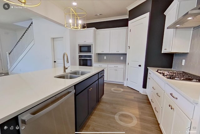 kitchen with stainless steel appliances, wall chimney exhaust hood, a sink, and white cabinetry