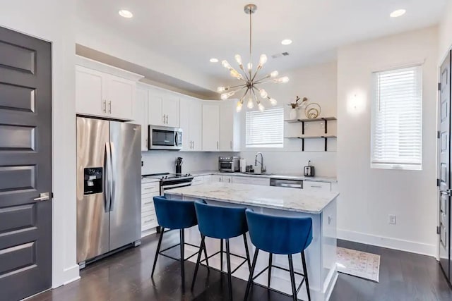 kitchen with sink, decorative light fixtures, appliances with stainless steel finishes, a kitchen island, and white cabinets