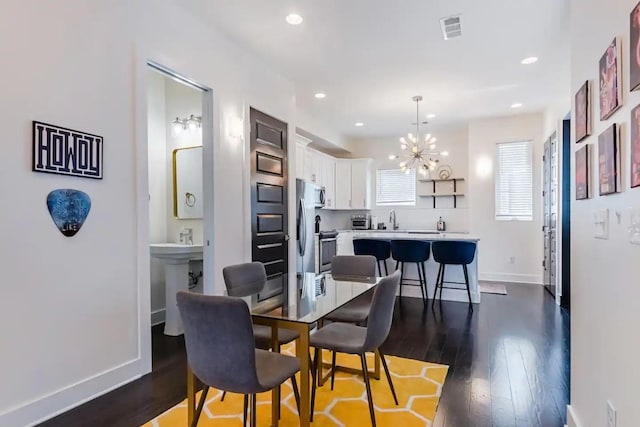 dining room featuring sink, hardwood / wood-style flooring, and a notable chandelier