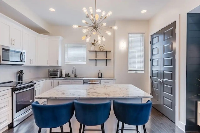 kitchen with a kitchen island, white cabinetry, sink, stainless steel appliances, and dark wood-type flooring