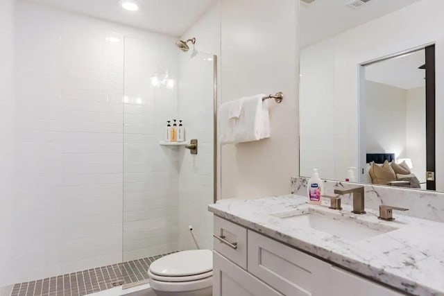 bathroom featuring vanity, toilet, and a tile shower