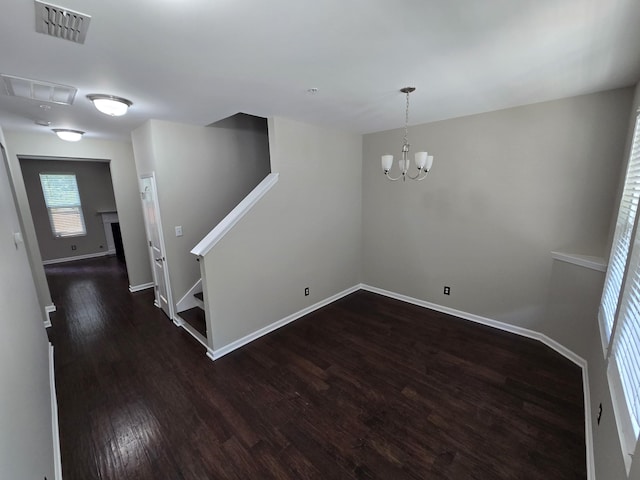 unfurnished room featuring dark wood-type flooring and a notable chandelier