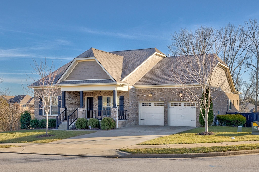 craftsman inspired home with a porch, a garage, and a front lawn