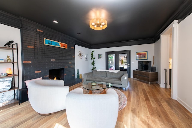 living room with crown molding, a brick fireplace, and light wood-type flooring