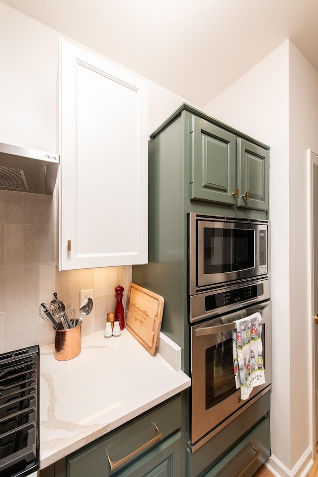 kitchen featuring tasteful backsplash, appliances with stainless steel finishes, white cabinets, and range hood