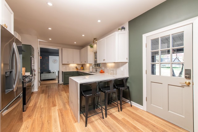 kitchen with stainless steel refrigerator with ice dispenser, white cabinetry, sink, and kitchen peninsula