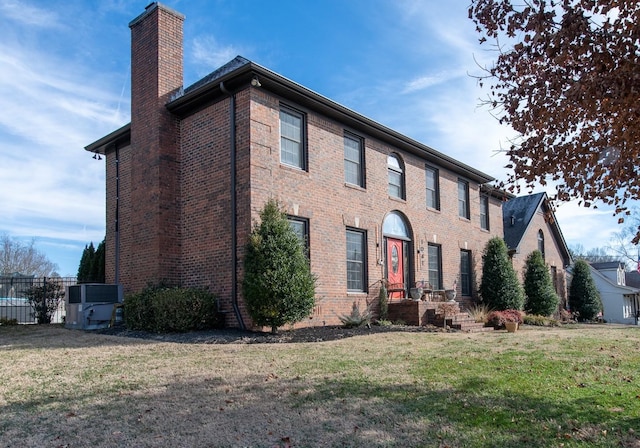 colonial home featuring a front lawn and central air condition unit