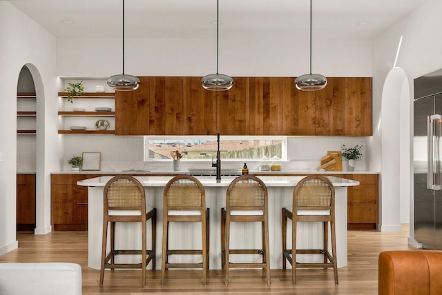 kitchen featuring pendant lighting, high end refrigerator, tasteful backsplash, and light hardwood / wood-style flooring