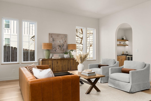 living room with bar, wine cooler, and light hardwood / wood-style floors