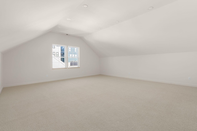 additional living space featuring lofted ceiling and light carpet