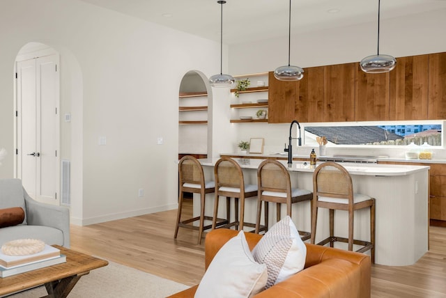 kitchen with a kitchen island, a kitchen breakfast bar, hanging light fixtures, and light hardwood / wood-style flooring