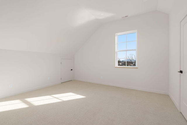 additional living space featuring vaulted ceiling and light carpet