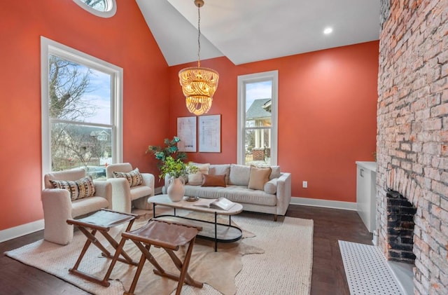 living room with an inviting chandelier, a healthy amount of sunlight, a fireplace, and high vaulted ceiling