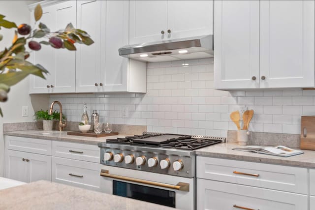 kitchen with white cabinetry, sink, gas range oven, and decorative backsplash