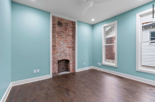 unfurnished living room featuring ceiling fan, a large fireplace, and dark hardwood / wood-style floors