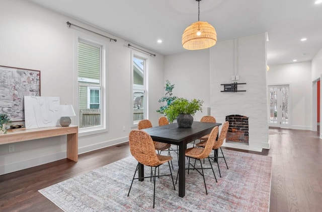 dining space with dark wood-type flooring and a large fireplace