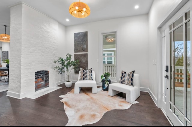 sitting room featuring a stone fireplace and dark wood-type flooring