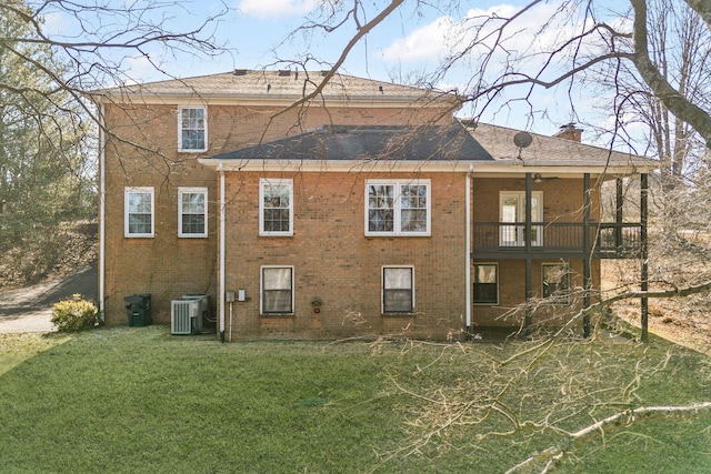 rear view of house with central AC unit and a lawn