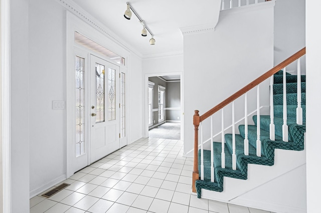 entrance foyer featuring light tile patterned floors, track lighting, and crown molding