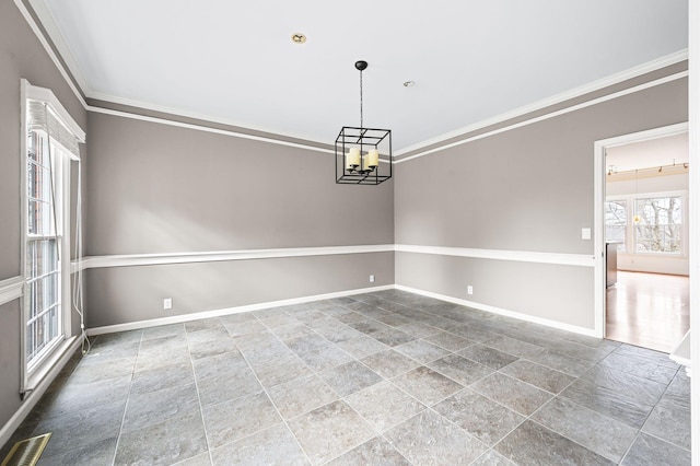 empty room with ornamental molding and a chandelier