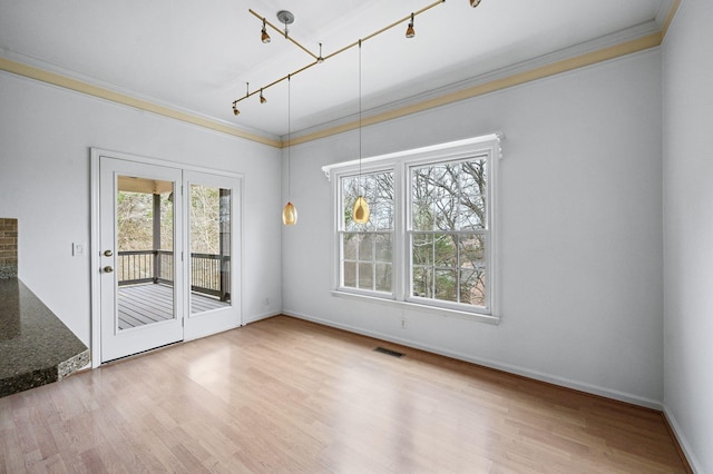 unfurnished dining area with light wood-type flooring, crown molding, and rail lighting