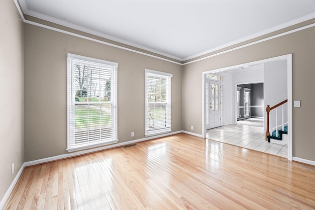 spare room featuring light wood-type flooring and crown molding