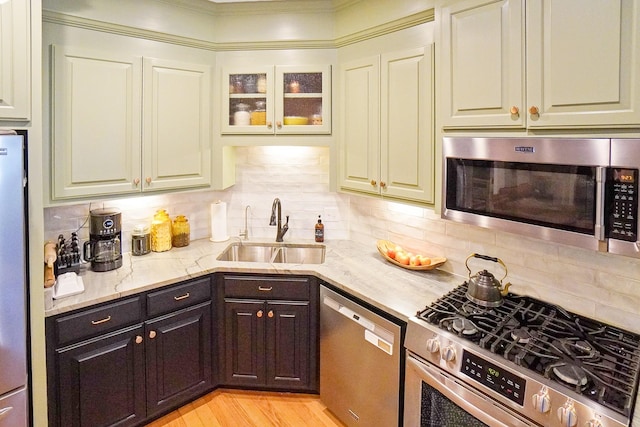 kitchen with light stone counters, sink, backsplash, and stainless steel appliances