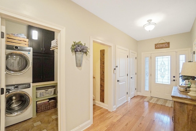 washroom featuring light wood-type flooring, cabinets, and stacked washing maching and dryer