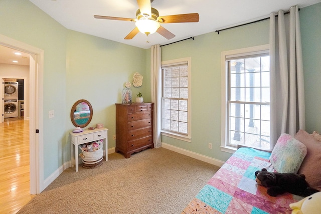 carpeted bedroom featuring ceiling fan and stacked washer / drying machine