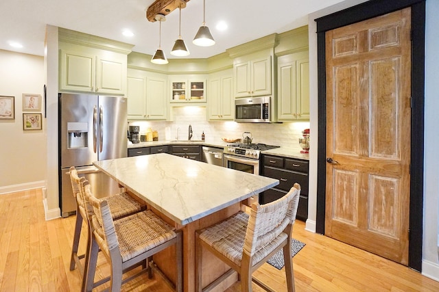 kitchen with light stone counters, decorative light fixtures, a center island, stainless steel appliances, and decorative backsplash