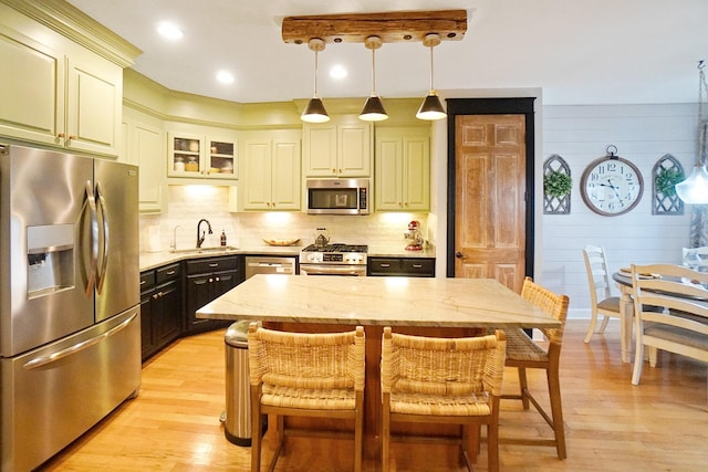 kitchen featuring appliances with stainless steel finishes, hanging light fixtures, sink, and a kitchen island