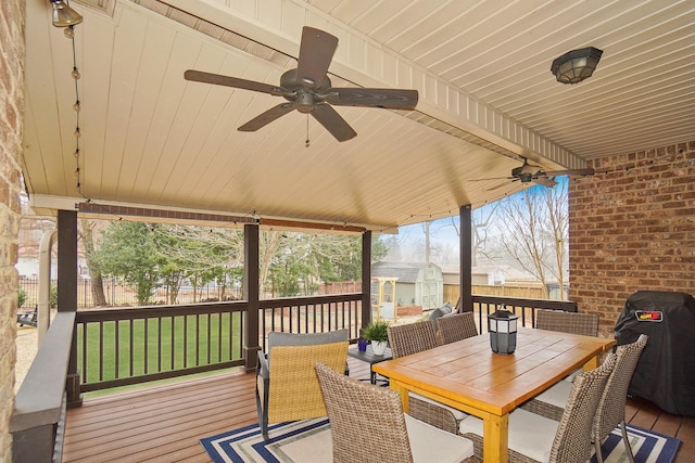 deck with ceiling fan, grilling area, a storage unit, and a lawn